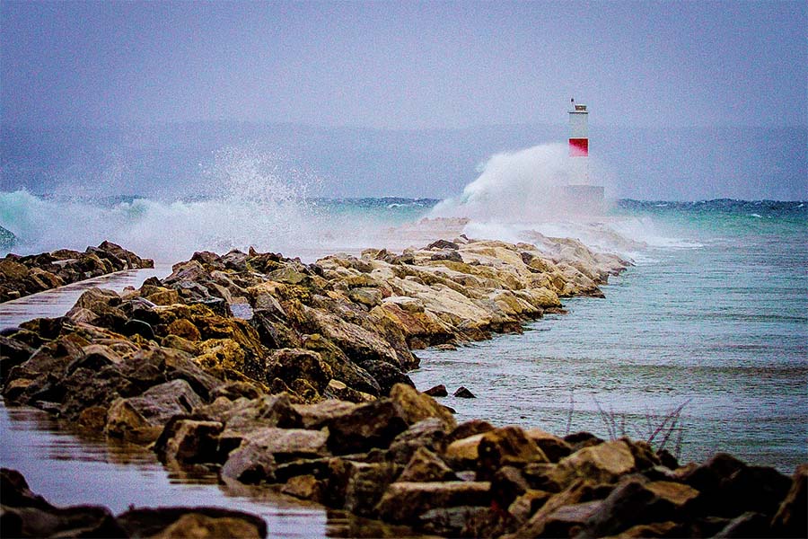 About Our Agency - View of Waves Crashing into Lighthouse and Jetty in Petoskey Michigan
