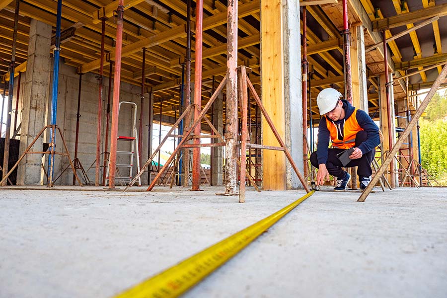Specialized Business Insurance - Portrait of a Contractor Measuring Floor Length While on a Building Construction Jobsite