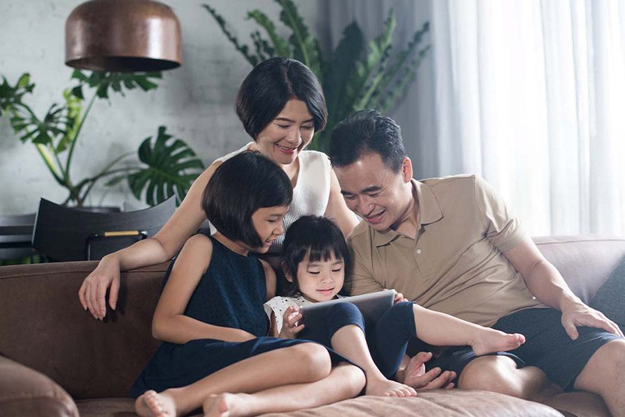 Umbrella Insurance - Happy Family Using a Tablet Together at on the Living Room Sofa of Their Modern Home